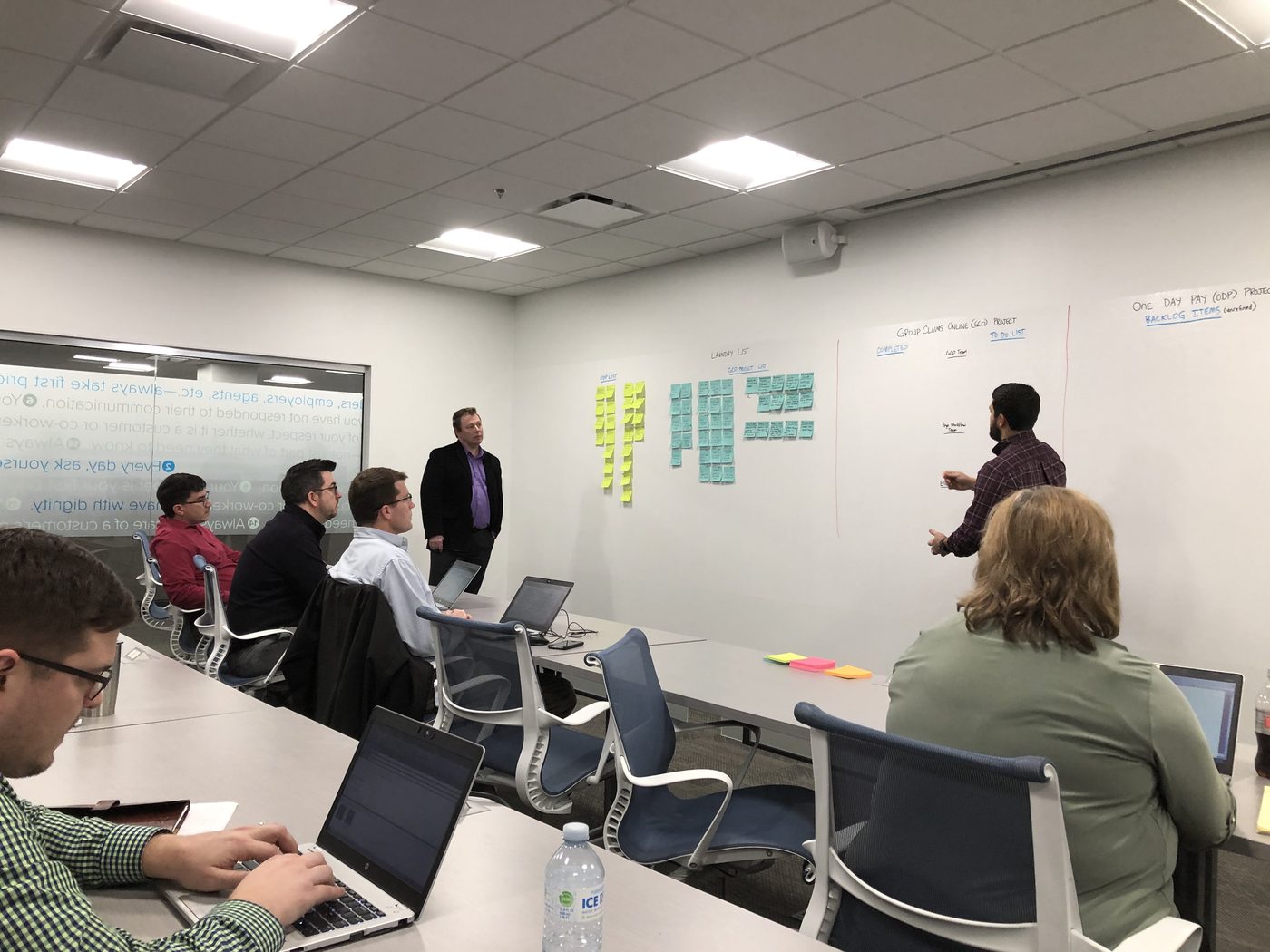 Signal & Horizon operators working through implementation planning with a client team — laptops, whiteboard backlog, real strategic work in progress
